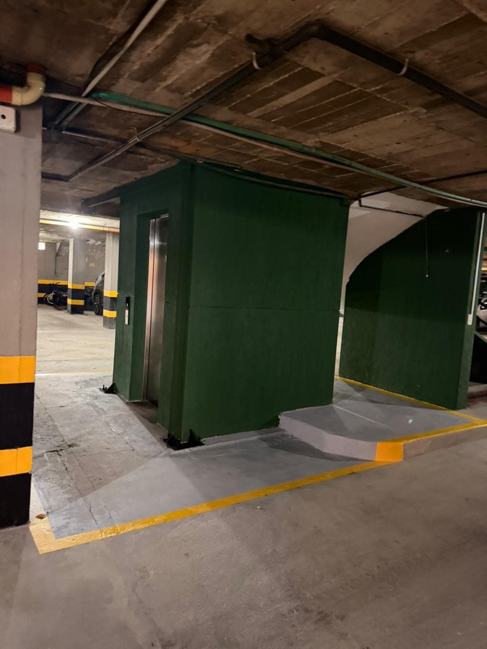Módulo del ascensor con acabado verde y acceso señalizado en el sótano del edificio La Quilla en Bogotá