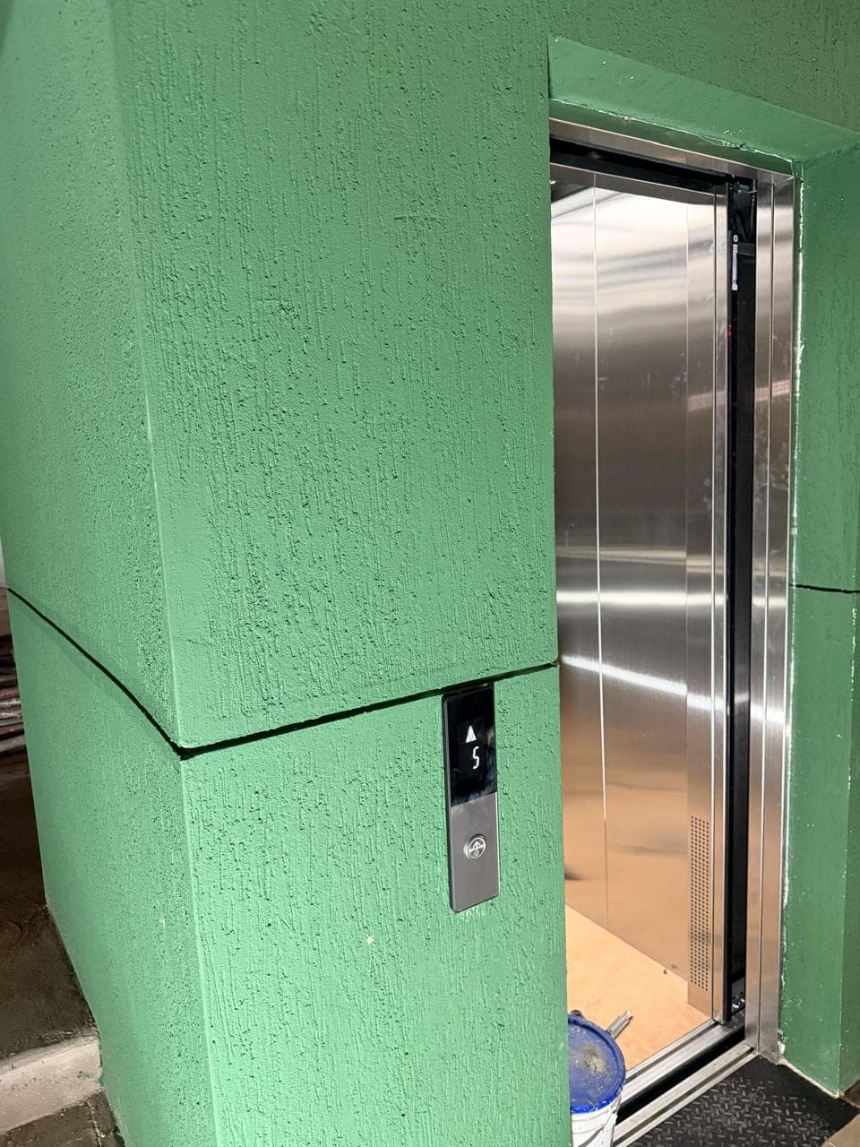 Acceso al ascensor con puerta abierta y botonera de piso en el quinto nivel del edificio La Quilla