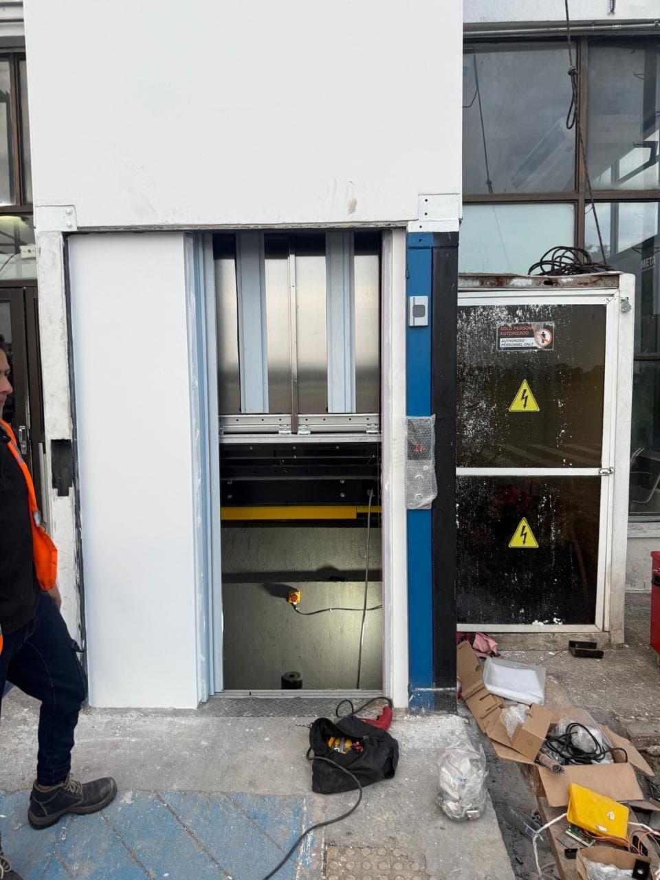 Frente del ascensor durante el montaje con el hueco abierto y herramientas de instalación en el Aeropuerto Vanguardia