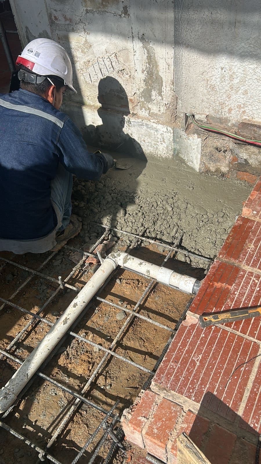 Técnico con casco fundiendo el concreto del foso del elevador hidráulico durante la obra civil en Ocaña