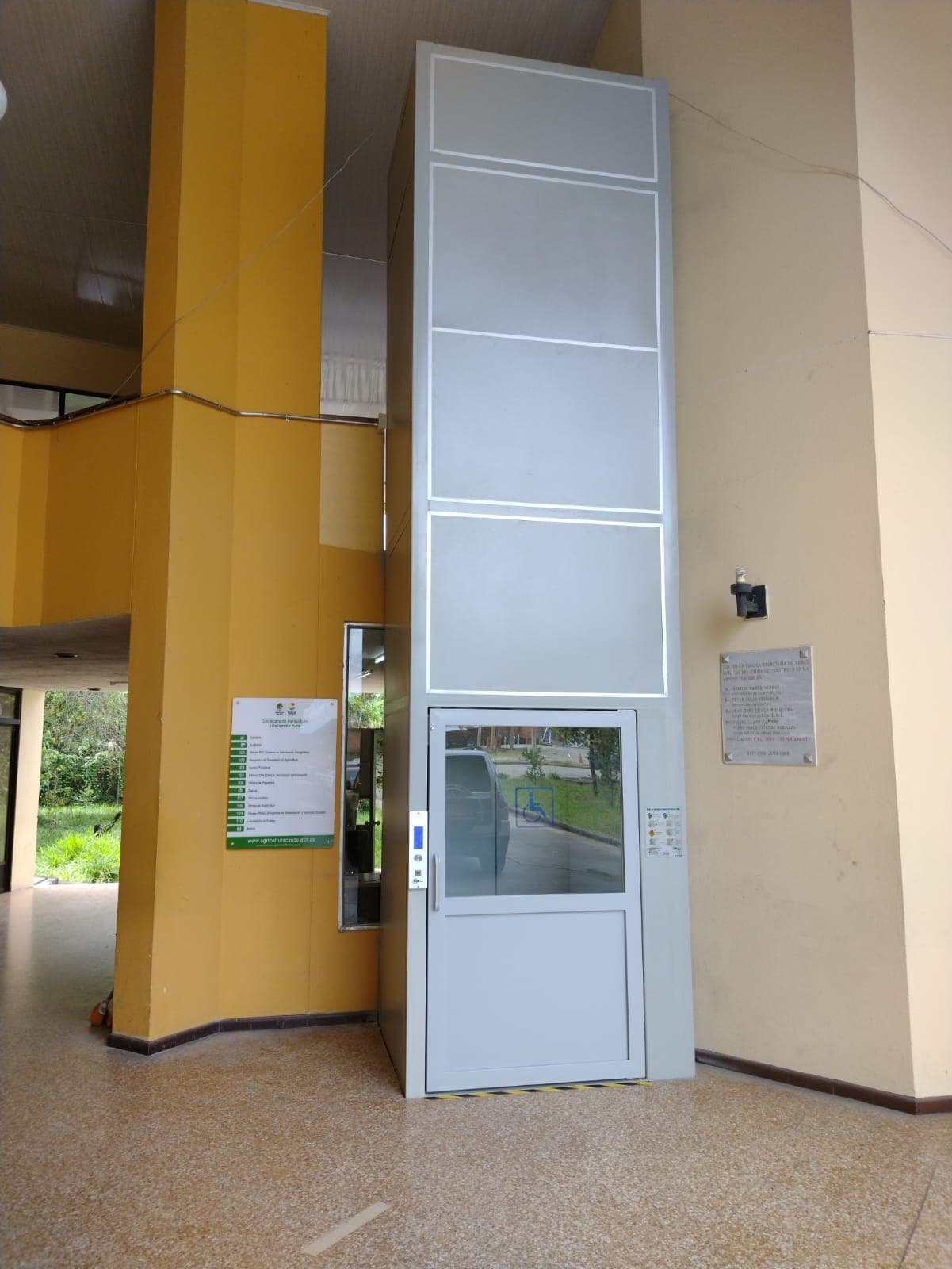Torre completa de la plataforma vertical con puerta de acceso y señalización de accesibilidad en la Gobernación del Cauca