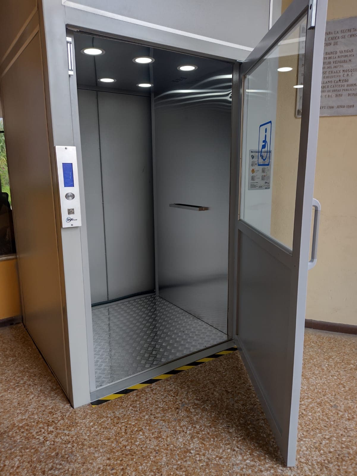 Detalle del interior en acero inoxidable de la cabina de la plataforma vertical con botonera y pasamanos