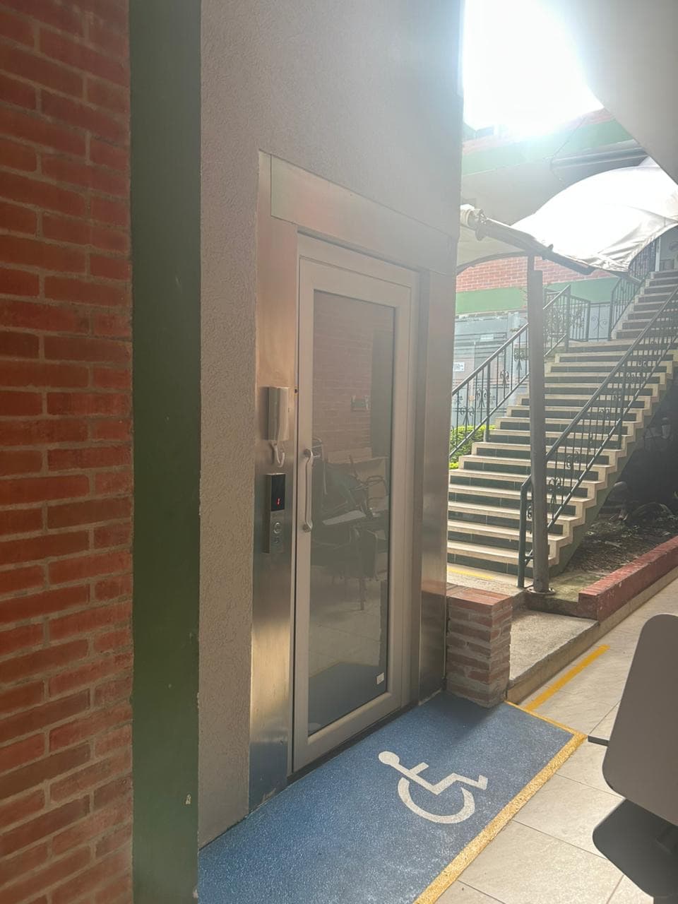 Acceso a la plataforma de accesibilidad con tapete de señalización para silla de ruedas junto a las escaleras del SENA de La Plata, Huila