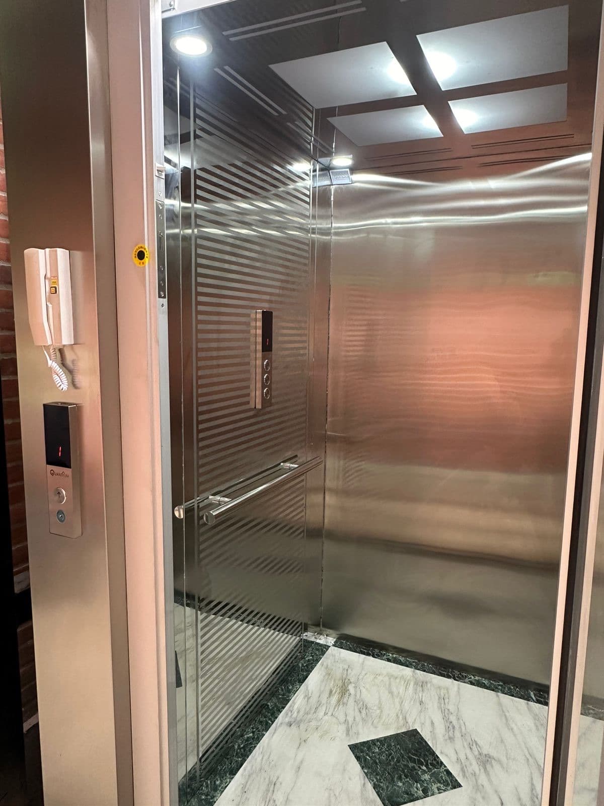 Interior de la cabina en acero inoxidable con iluminación led y piso de mármol de la plataforma del SENA de La Plata