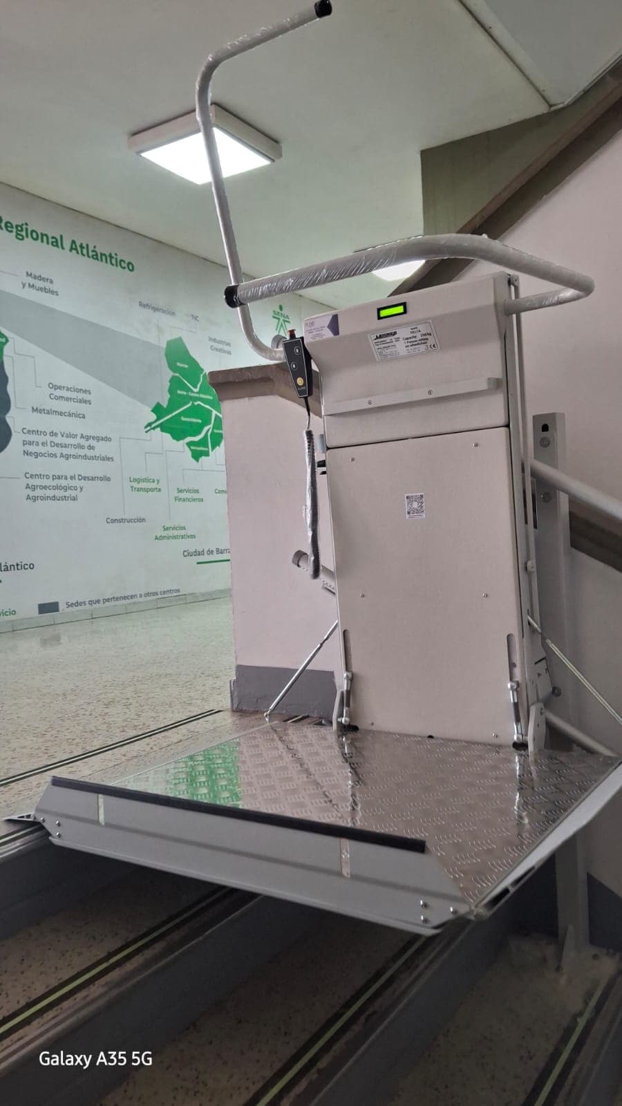 Plataforma salvaescaleras plegada en posición de reposo al inicio de la escalera del SENA de Barranquilla