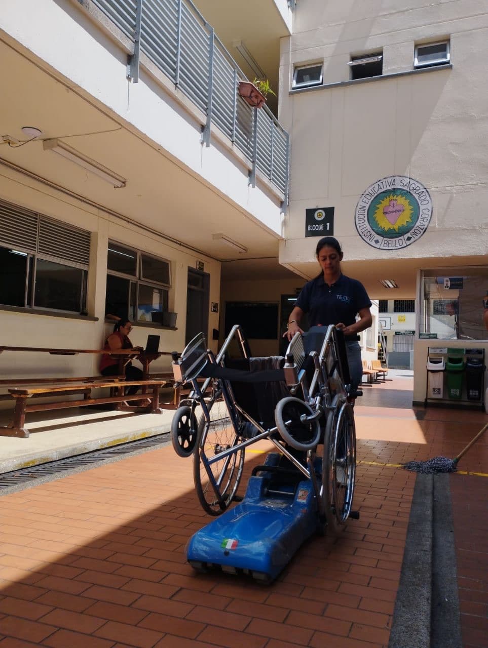 Técnica de Quantium operando la silla salvaescalera tipo oruga con silla de ruedas en la Institución Educativa Sagrado Corazón de Bello, Antioquia